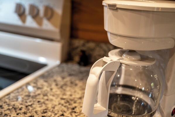 A coffee maker with a clear water reservoir and a white base, placed on a granite countertop. - Book NOW and receive tickets to Dollywood, Anakeesta and many more (Gatlinburg)