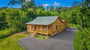 Une cabane en rondins dotée d’un porche et d’un escalier menant à l’entrée.