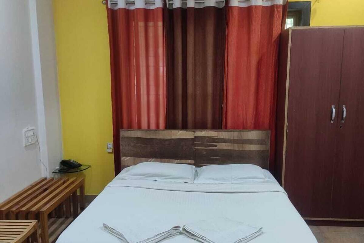 A bedroom with a bed, a wooden bench, a wardrobe, and a ceiling fan.