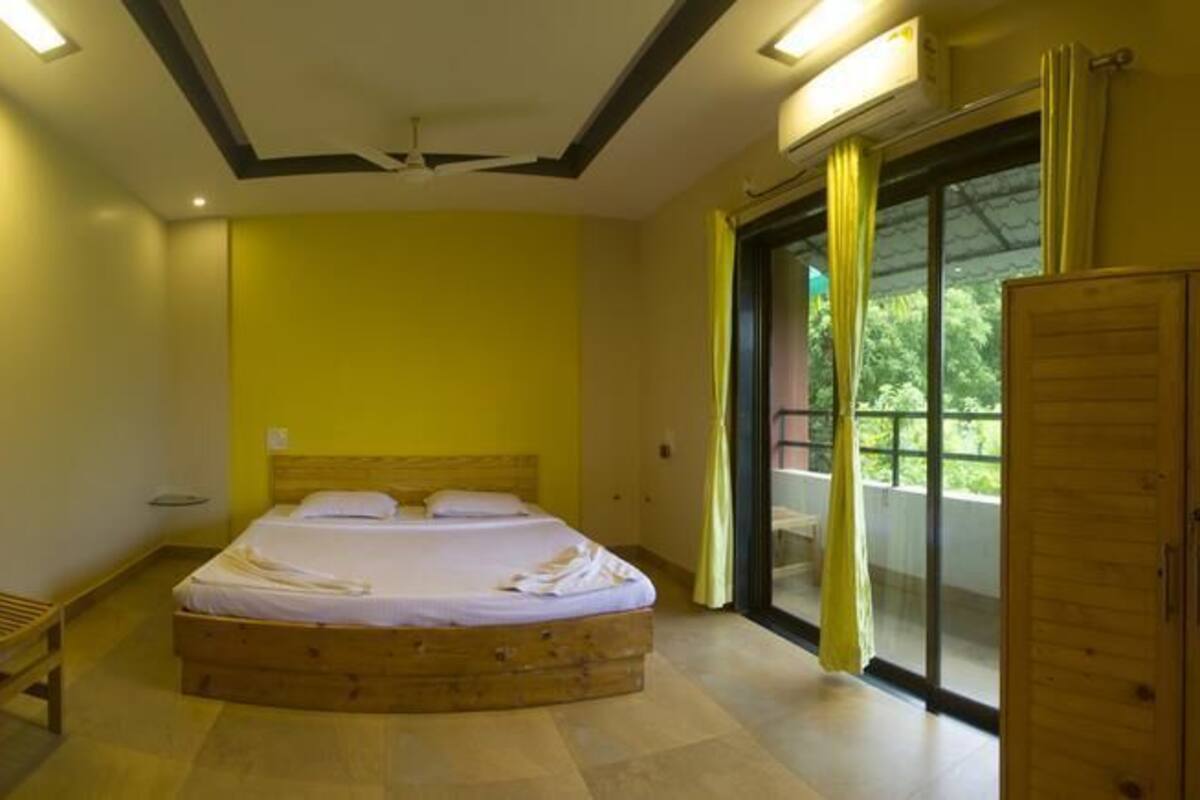 A bedroom with a bed, a chair, a wardrobe, and a sliding glass door leading to an outdoor area.