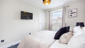Un dormitorio con cama, un letrero que dice 'Luxury Stay', una ventana con cortinas y una lámpara fijada a la pared.