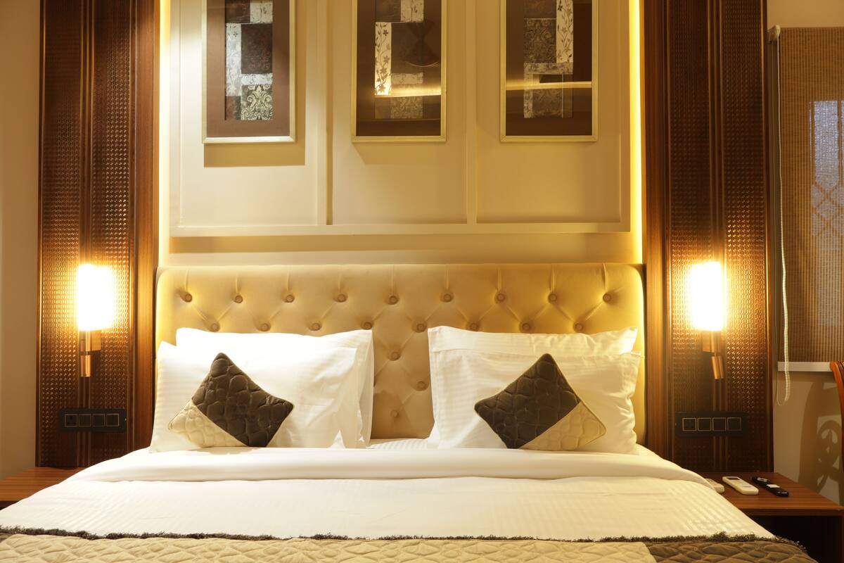 Ein Hotelzimmer mit einem großen Bett, zwei Nachttischen, einem fest montierten Telefon und gerahmten Bildern über dem Bett.