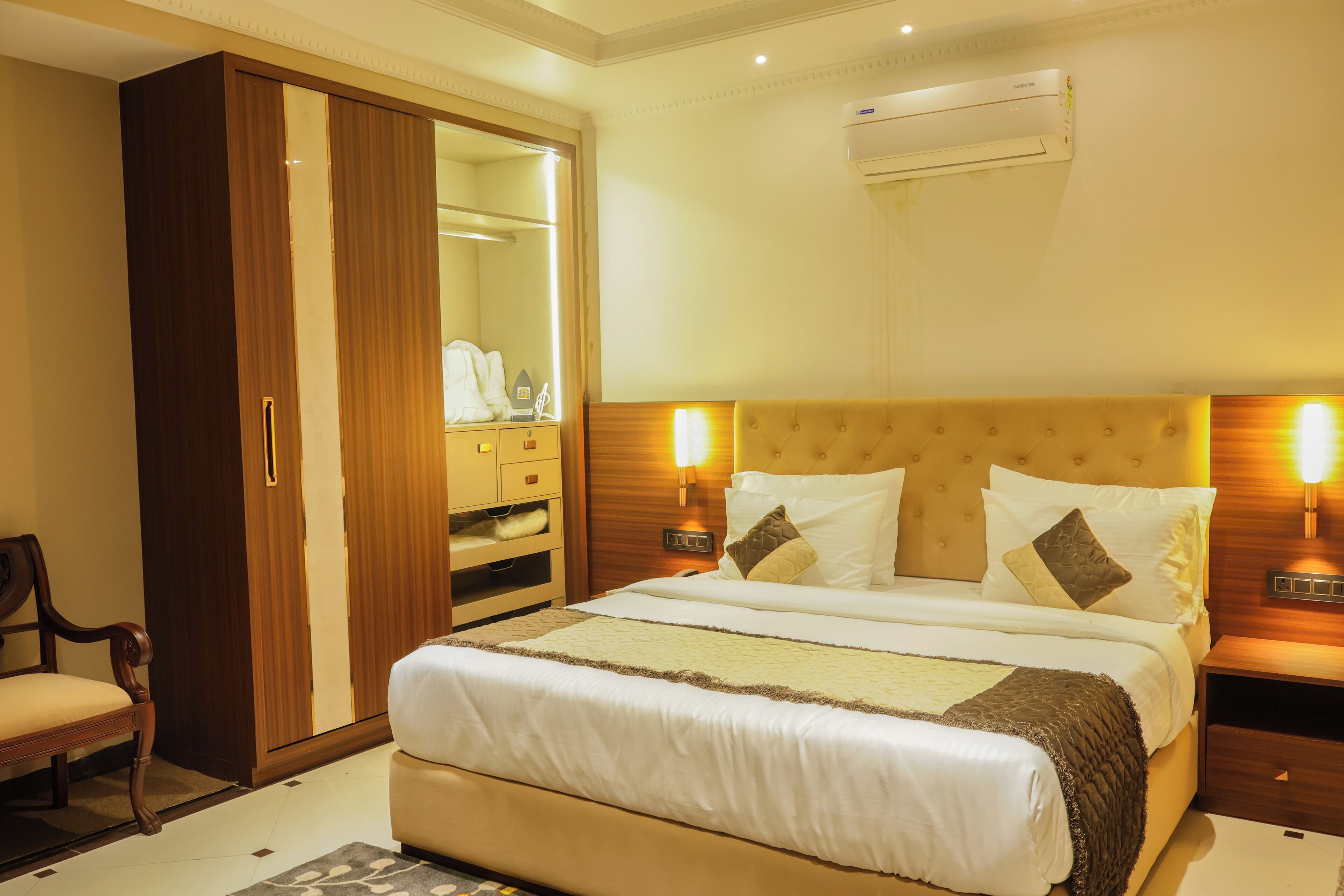 Een hotelkamer met een groot bed, een kledingkast, een spiegel en een airconditioning.