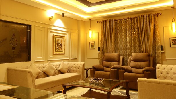 A well-lit living room with a sofa, armchairs, and a glass coffee table. - Suramya (Bhopal)