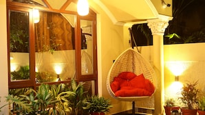 A cozy indoor space with a hanging chair, potted plants, and a large window. - Suramya (Bhopal)