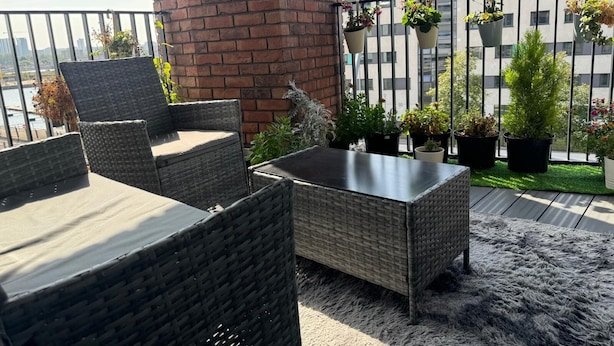 A balcony with wicker furniture, potted plants, and a view of the cityscape. - London City Chic Apartment With 3 Bedrooms (London)