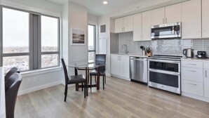 A modern kitchen with white cabinets, stainless steel appliances, and a dining area with a table and chairs. - Private Apt Downtown (Quincy)