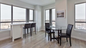 A modern kitchen with white cabinets, a dining table with chairs, and large windows offering a city view. - Private Apt Downtown (Quincy)