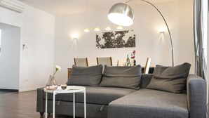 Una sala de estar moderna con un sofá seccional gris, una mesita auxiliar blanca y una lámpara de pie.