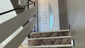 Una escalera con escalones de mármol que conduce a una puerta con un panel de vidrio esmerilado.