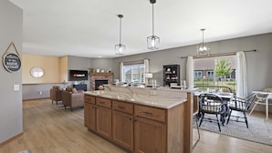 A modern kitchen with wooden cabinets, a large island, pendant lighting, and a view of the outdoors. - 25min to Capitol - KING Suite - Game Room - Groups (Stoughton)