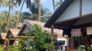 Een tropisch resort met meerdere bungalowachtige accommodaties, omringd door weelderige begroeiing en palmbomen.