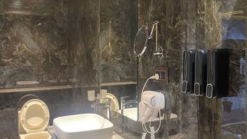 A modern bathroom with a large mirror, a toilet, a sink, and a hairdryer.