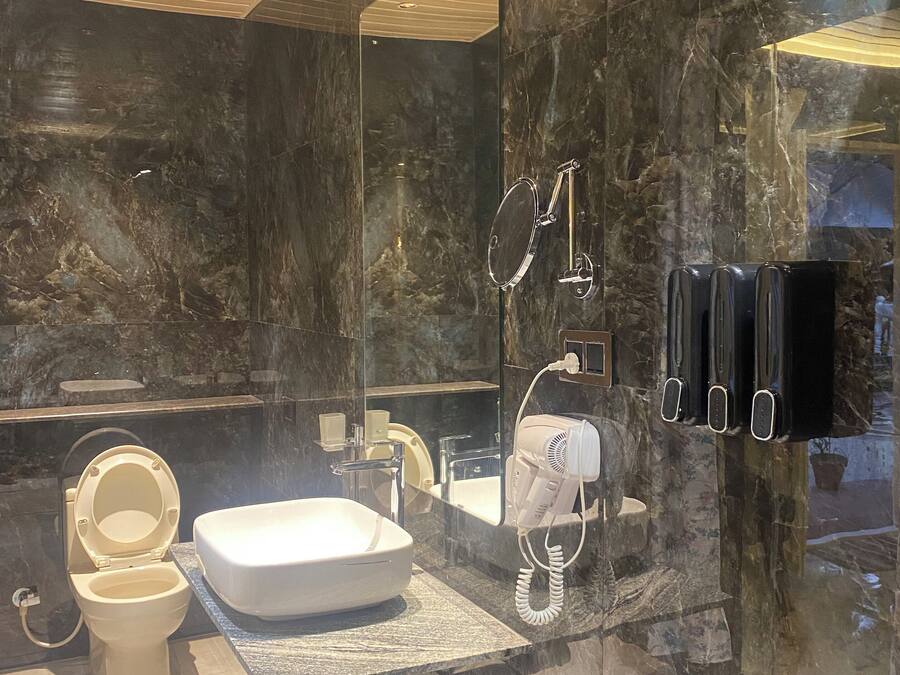 A modern bathroom with a large mirror, a toilet, a sink, and a hairdryer.