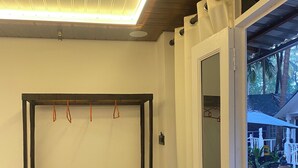 Een kamer met een houten bank, een plafondlamp en een deur naar buiten.