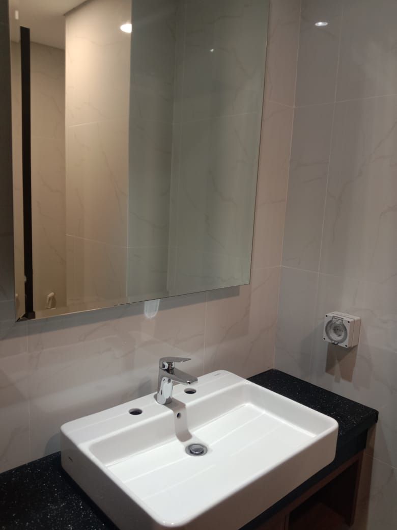 A bathroom with a white sink, a mirror, and a black countertop.