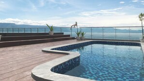 A pool with a tiled edge, surrounded by a wooden deck and potted plants.
