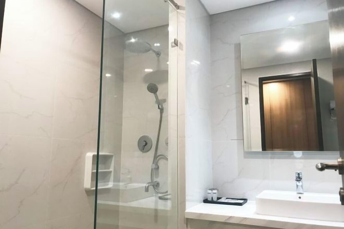 A modern bathroom with a glass-enclosed shower, a white sink, and a large mirror.