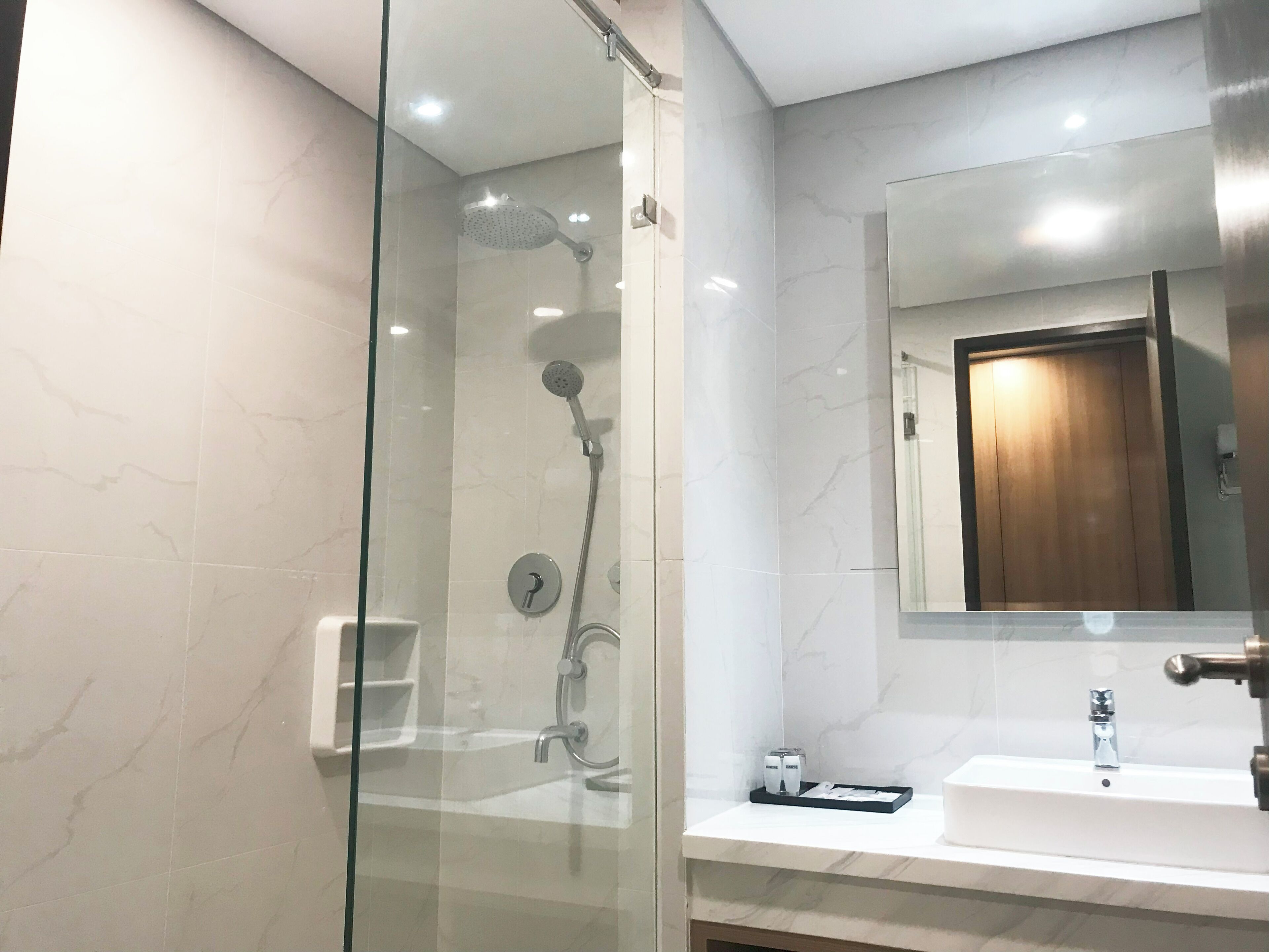 A modern bathroom with a glass-enclosed shower, a white sink, and a mirror above it.