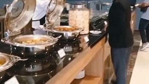 A buffet area with multiple food stations, including a hot grill and a variety of dishes in containers.