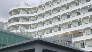 A multi-story hotel with a curved facade, balconies, and a glass walkway.