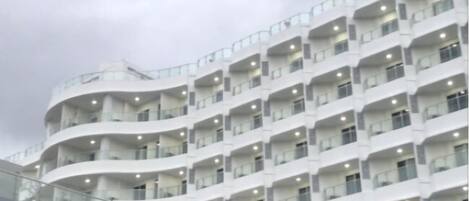 A multi-story hotel with a curved facade, balconies, and a glass walkway.