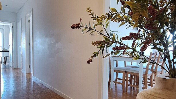 Un hall d’entrée spacieux avec un plancher en bois, un coin repas avec une table et des chaises, et une grande fenêtre.