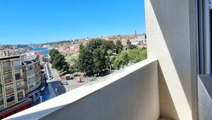 Un balcon offrant une vue dégagée sur le paysage urbain, avec des bâtiments et une étendue d’eau.