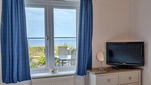 Ein Zimmer mit Fenster, Fernseher, kleinem Tisch und Stuhl.