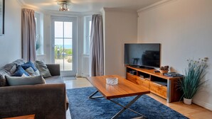 Ein modernes Wohnzimmer mit einer Couch, einem Couchtisch, einem Fernseher und einer Holz-Unterhaltungseinheit.