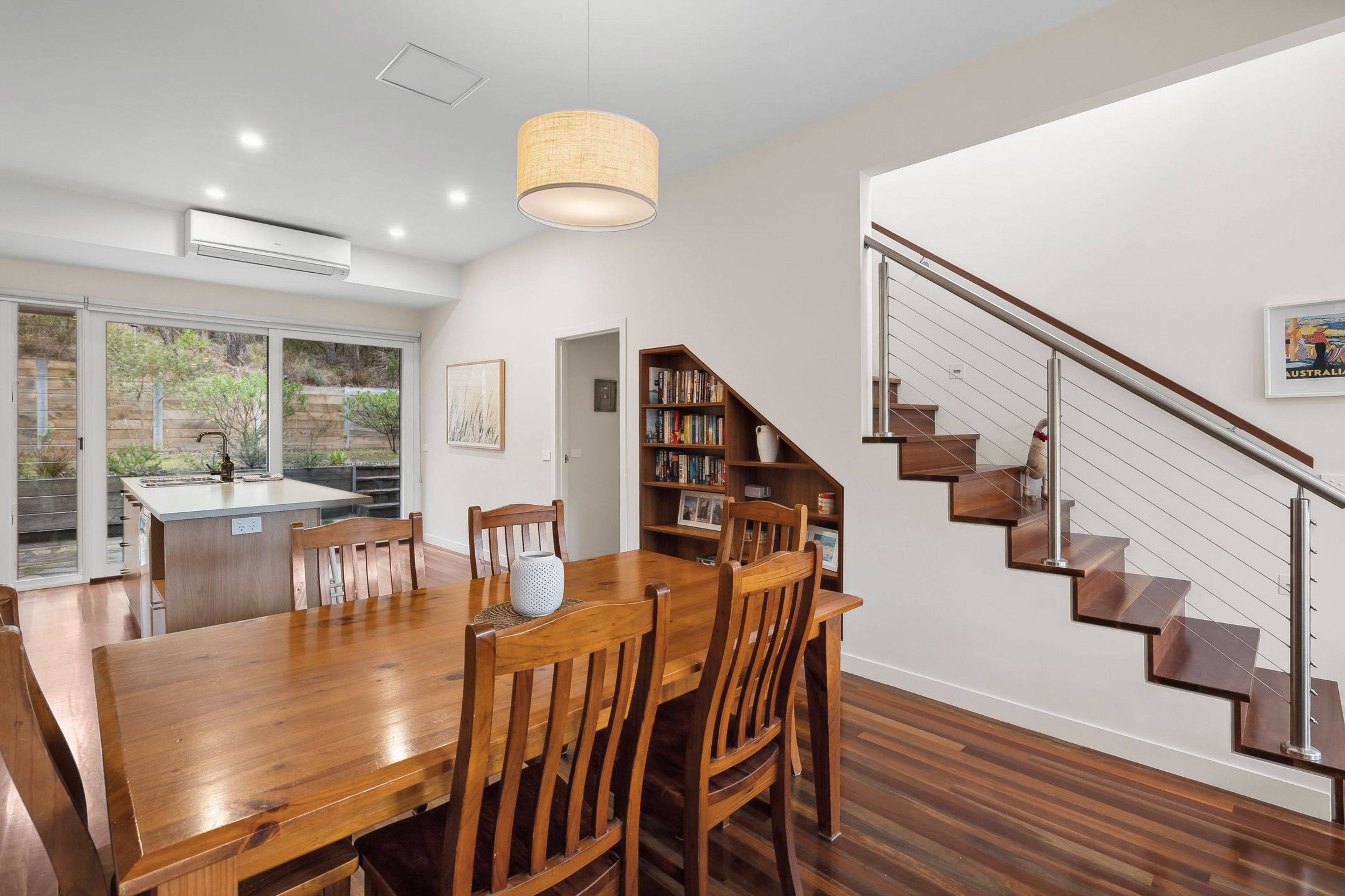 A modern kitchen with a dining area, wooden furniture, and a staircase.