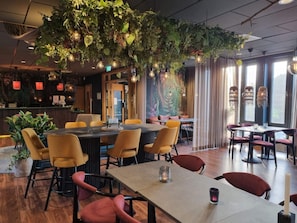 Un restaurant doté d’un plafond haut, de plantes suspendues et d’un éclairage moderne. Les tables et les chaises sont disposées de manière à faciliter la restauration.