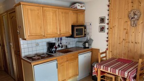 A compact kitchen with wooden cabinets, a microwave, a coffee maker, and a sink.