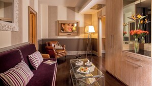 A modern hotel room with a purple sofa, a glass coffee table, a leather armchair, and a large mirror. - The Inn at the Spanish Steps Luxury Collection - Spanish Steps Suites (Rome)
