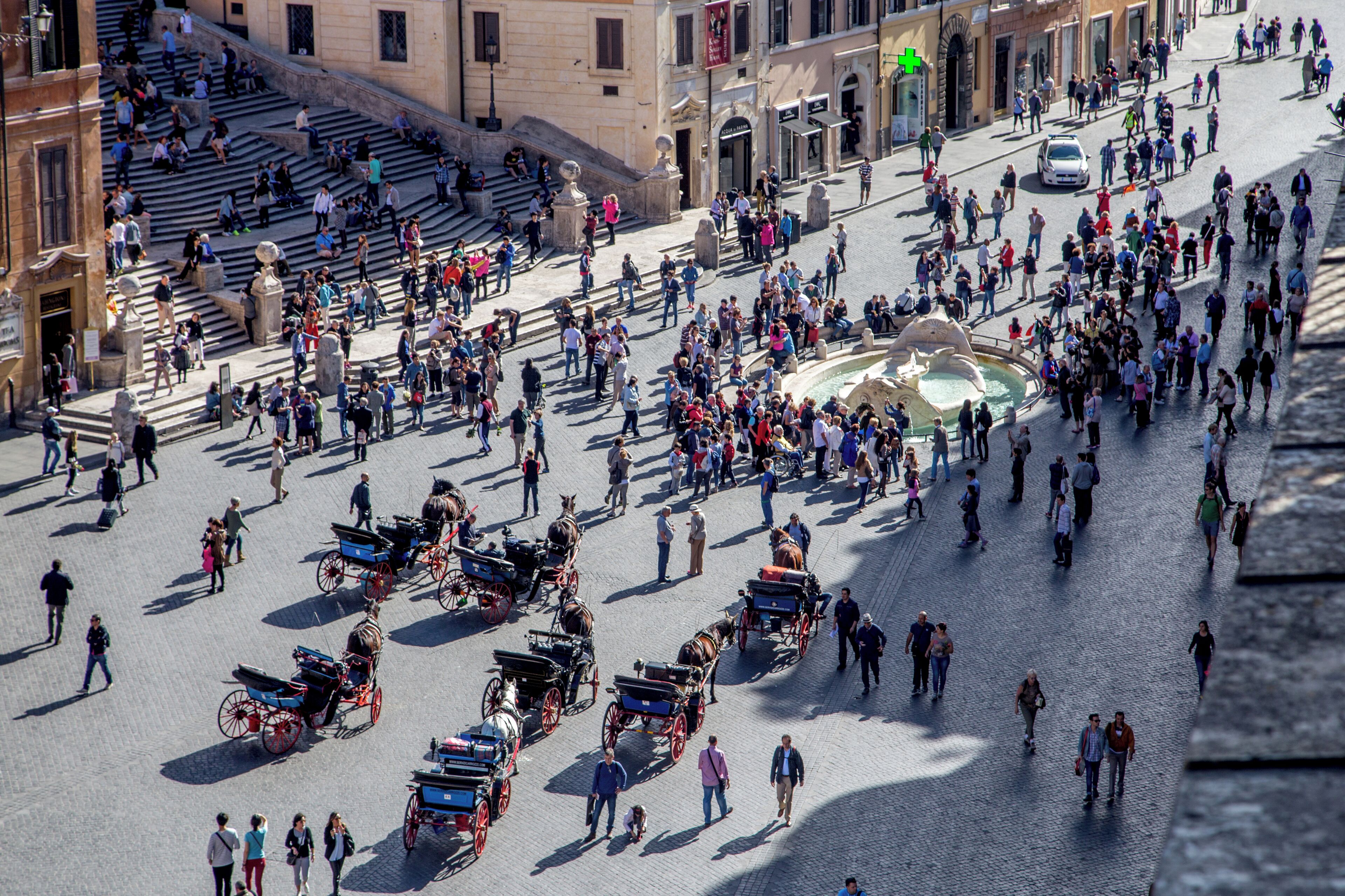 A bustling square with multiple horse-drawn carriages and pedestrians.