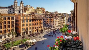 A bustling square with historic buildings, a prominent church, and a flower-adorned balcony. - The Inn at the Spanish Steps Luxury Collection - Spanish Steps Suites (Rome)