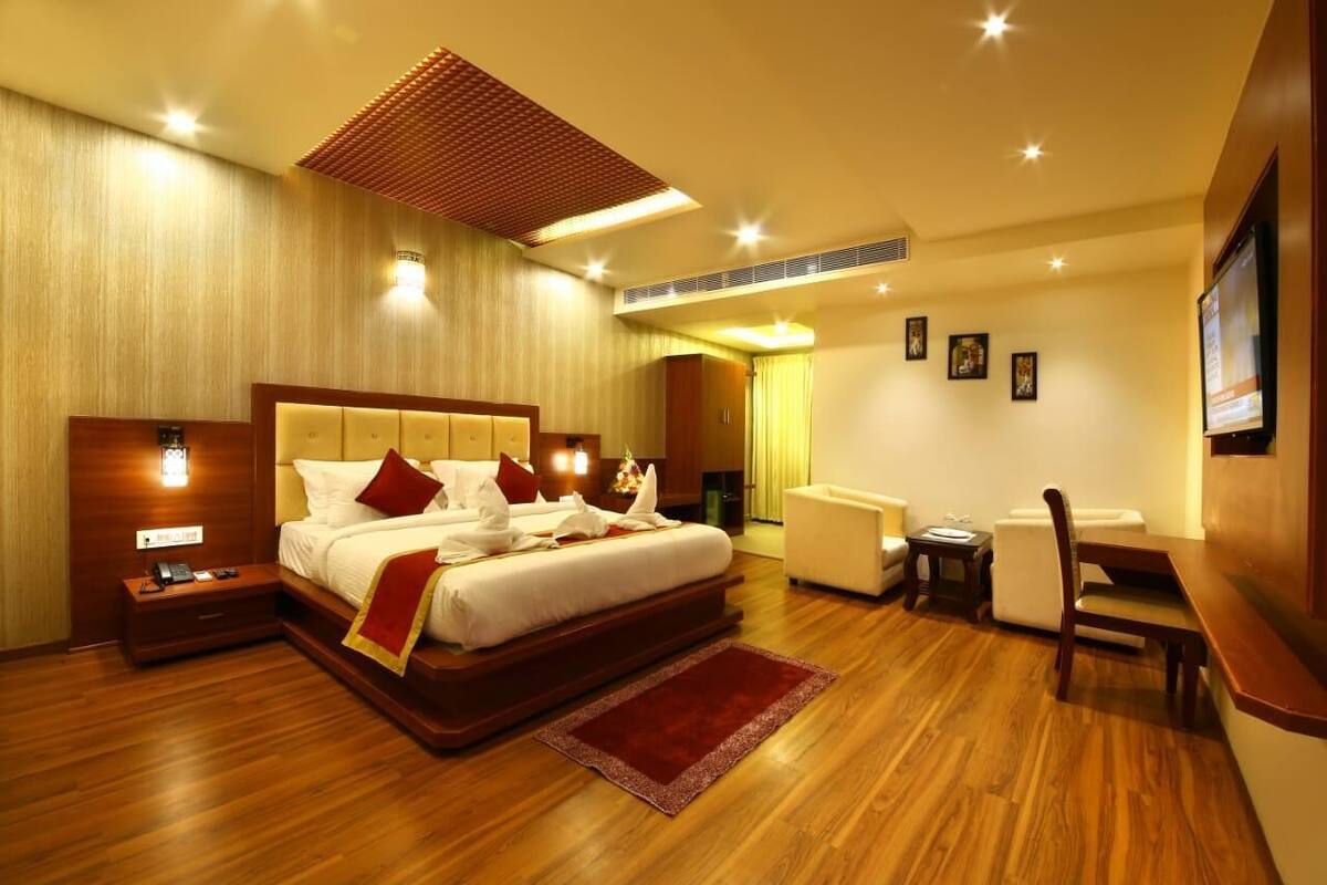 A spacious hotel room with a large bed, bedside tables, a desk, and a chair.