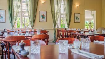 A dining area with wooden tables and chairs, each set with clear glassware and napkins.