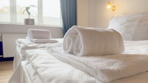A neatly made bed with white linens and a rolled towel on top. - Morup Mølle Kro (Bedsted)