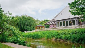 A riverside building with a gazebo, a covered walkway, and a fence. - Morup Mølle Kro (Bedsted)