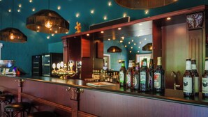 A bar area with a counter displaying various bottles, hanging pendant lights, and a reflective surface. - Morup Mølle Kro (Bedsted)
