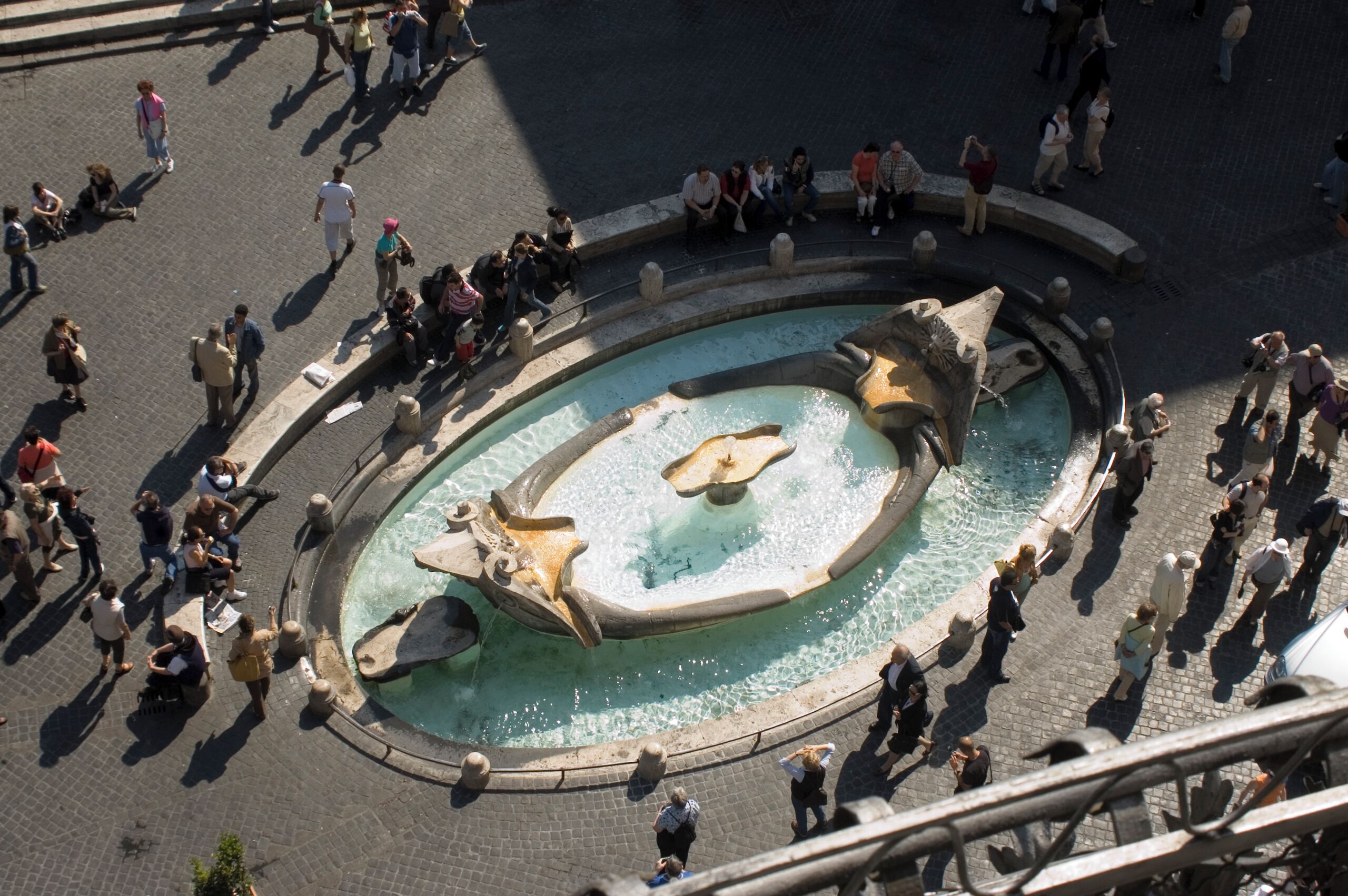 An aerial view of a public square with a central fountain, surrounded by people.