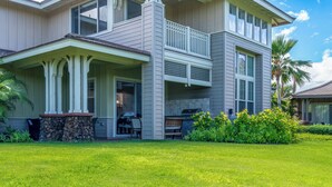 A two-story house with a covered porch, a stone wall, and a well-maintained lawn.