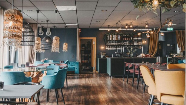 A restaurant interior with wooden flooring, blue and yellow chairs, hanging light fixtures, and a bar area. - 4 Star Holiday Home in Hisings Backa (Hisings Backa)