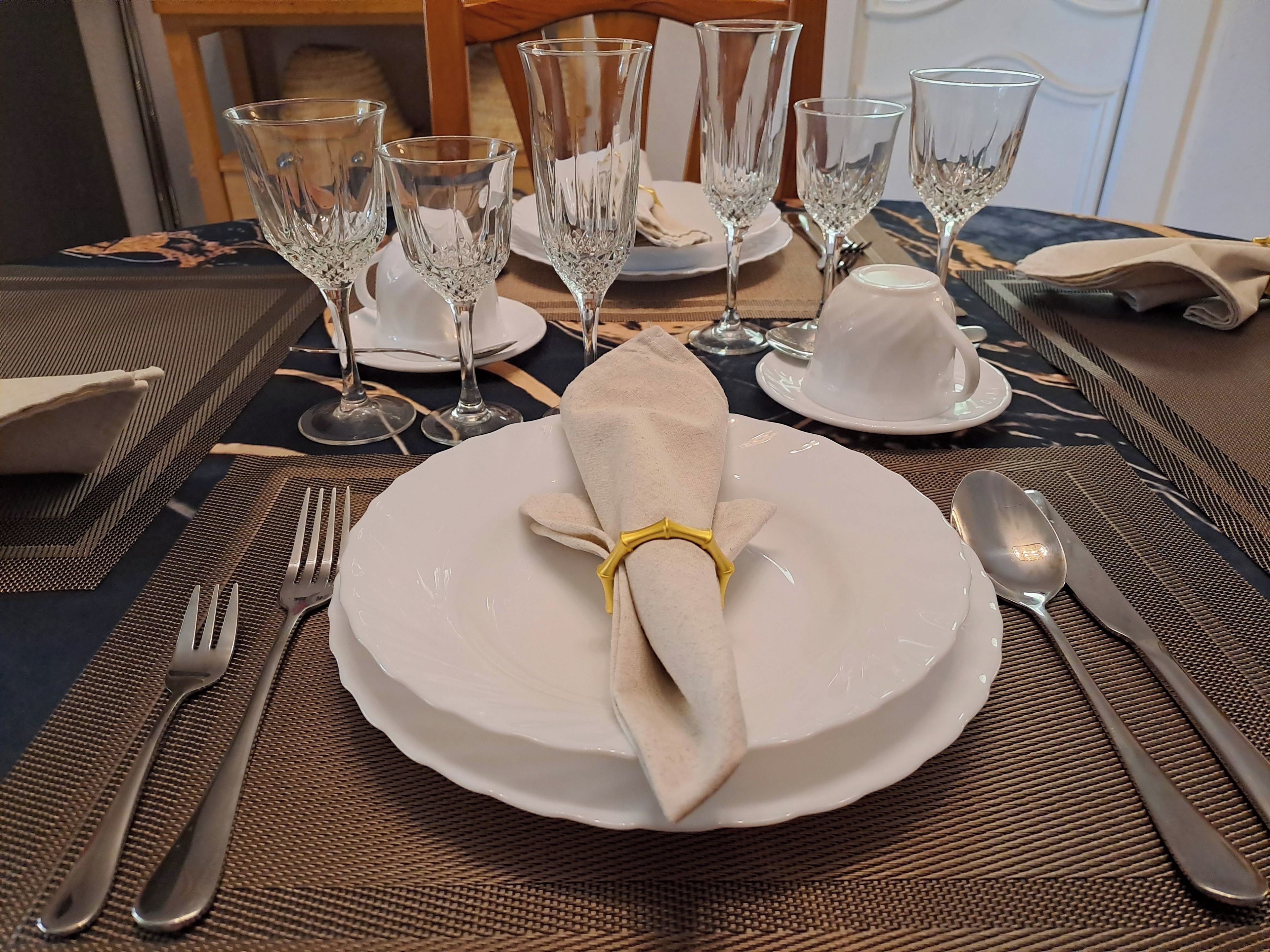 Een gedekte tafel met witte borden, bestek en kristallen glazen, wat wijst op een formele dineropstelling.