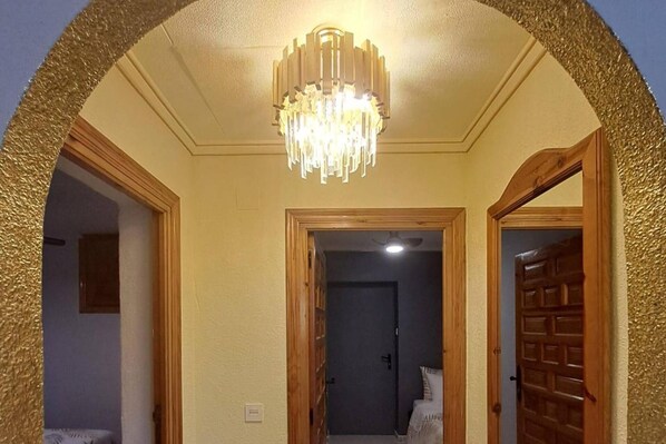 A room with a chandelier, wooden door frames, and a light switch on the wall.