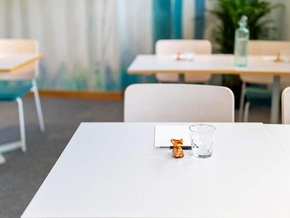 Una habitación moderna y limpia, con una mesa blanca, un vaso y un pequeño objeto envuelto encima.