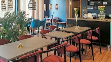 En restauranginteriör med bord och stolar, en bardisk och dekorativ belysning.