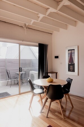 Un espace repas moderne avec une table ronde, des chaises noires et un vase jaune.