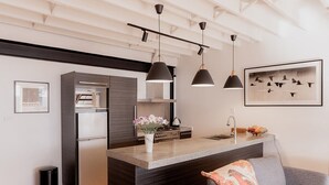 A modern kitchen with a central island, stainless steel appliances, pendant lighting, and a framed artwork on the wall. - Urban Warehouse Retreat in West Hobart (West Hobart)